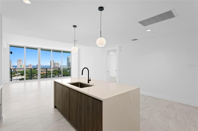 kitchen with a center island with sink, pendant lighting, dark brown cabinetry, and sink