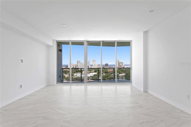empty room with baseboards, a city view, and floor to ceiling windows