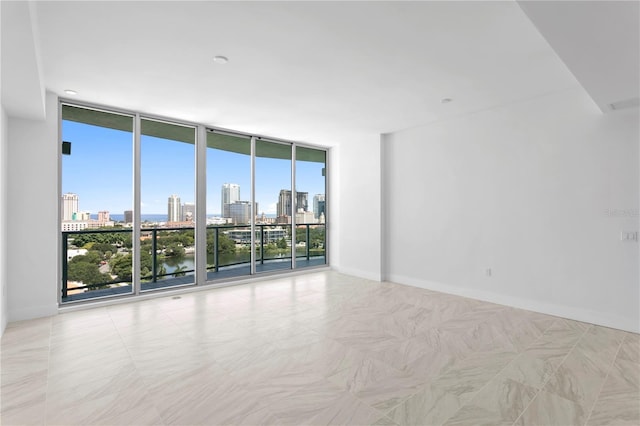 spare room with a city view, floor to ceiling windows, and baseboards