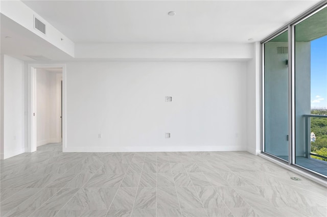 unfurnished room with visible vents, baseboards, and expansive windows