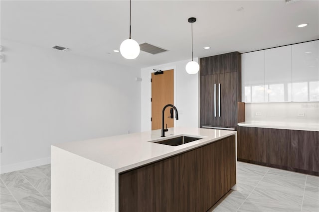 kitchen with paneled refrigerator, visible vents, modern cabinets, a sink, and light countertops