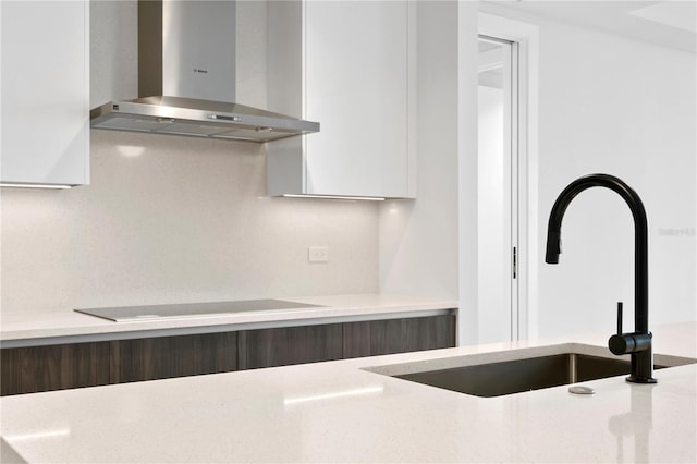 kitchen featuring modern cabinets, wall chimney exhaust hood, black electric stovetop, and a sink