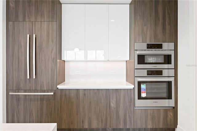 kitchen featuring light countertops, modern cabinets, and stainless steel double oven