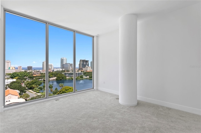 carpeted spare room with a view of city, baseboards, and expansive windows