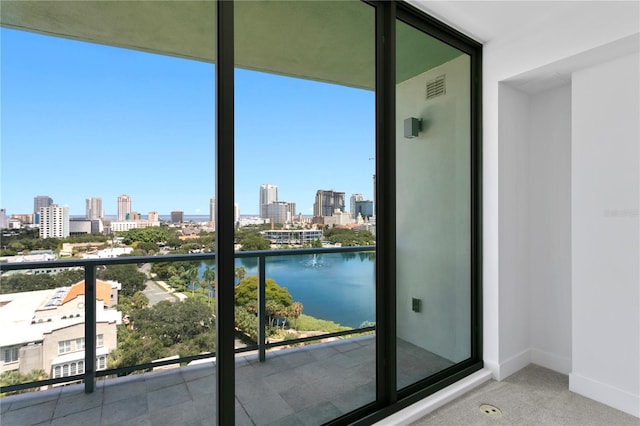 balcony featuring a city view, visible vents, and a water view