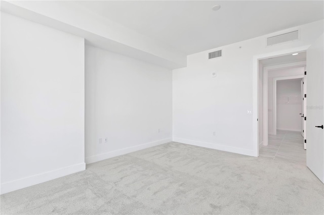 carpeted spare room featuring visible vents and baseboards