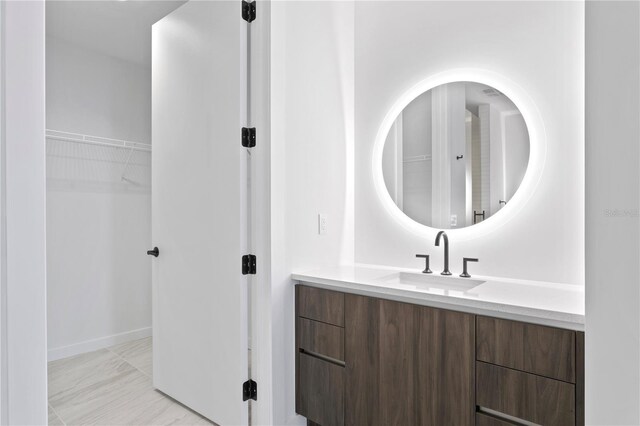 bathroom with a walk in closet, marble finish floor, and vanity