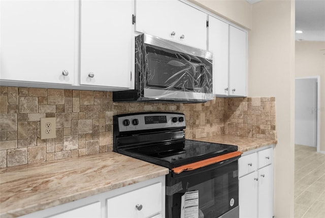 kitchen featuring white cabinetry, stainless steel appliances, decorative backsplash, light stone countertops, and light hardwood / wood-style floors