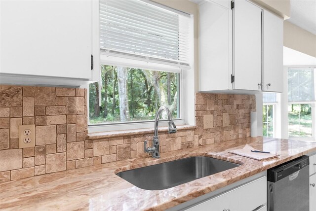 kitchen with stainless steel dishwasher, a healthy amount of sunlight, and tasteful backsplash