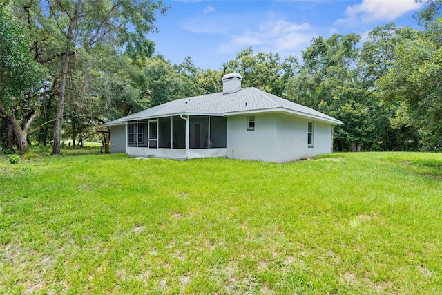 back of property featuring a sunroom and a lawn