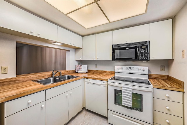 kitchen with white appliances, sink, light tile patterned floors, white cabinets, and butcher block countertops