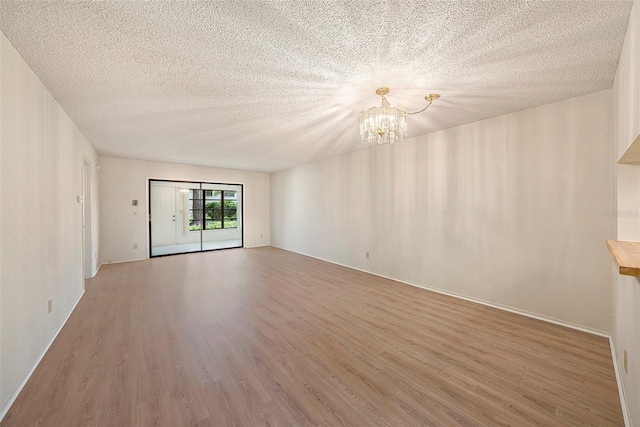 empty room with hardwood / wood-style floors, a chandelier, and a textured ceiling