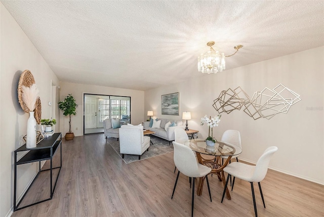 dining space with an inviting chandelier, hardwood / wood-style flooring, and a textured ceiling