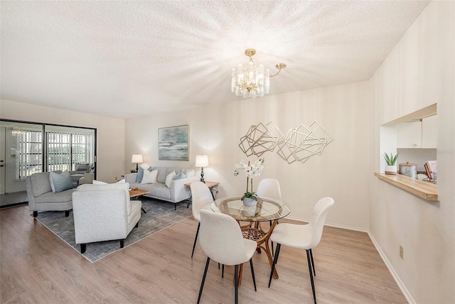 dining area with hardwood / wood-style flooring, a notable chandelier, and a textured ceiling