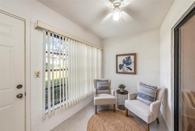 living area with ceiling fan, a textured ceiling, and carpet flooring