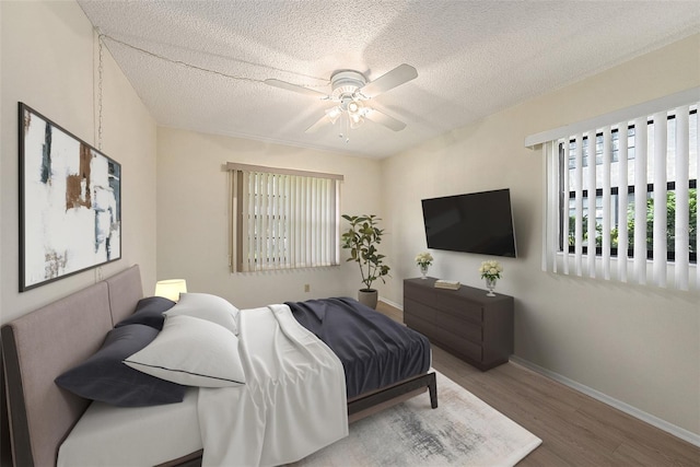 bedroom with ceiling fan, hardwood / wood-style flooring, and a textured ceiling