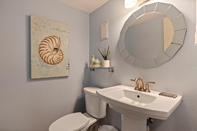 bathroom with toilet, sink, and a textured ceiling