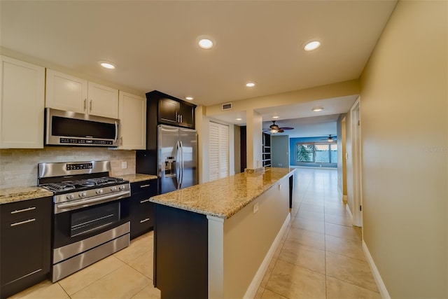 kitchen featuring a kitchen island, appliances with stainless steel finishes, white cabinets, and decorative backsplash