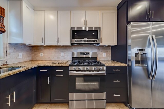 kitchen featuring white cabinetry, light stone countertops, tasteful backsplash, and stainless steel appliances