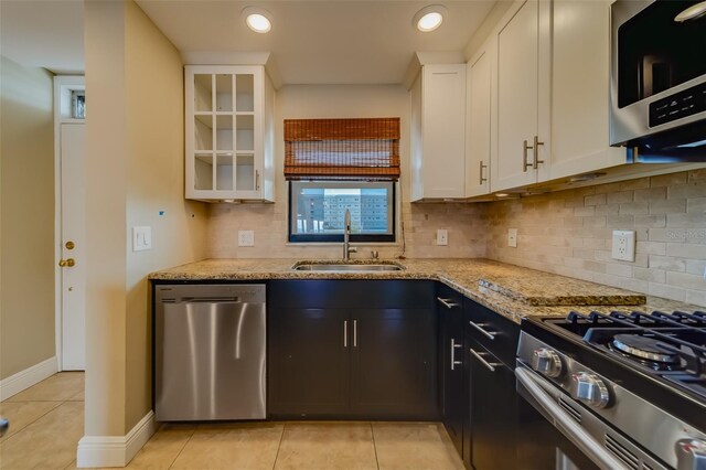 kitchen with white cabinetry, stainless steel appliances, light stone countertops, and sink