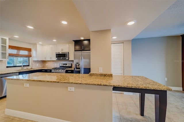 kitchen featuring tasteful backsplash, light stone countertops, appliances with stainless steel finishes, and sink