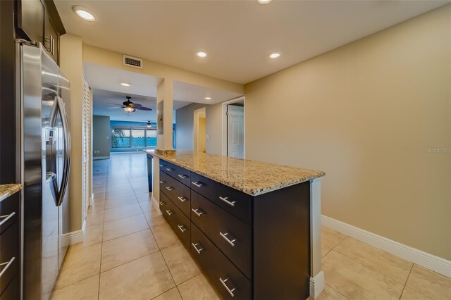 kitchen featuring light stone counters, stainless steel fridge with ice dispenser, a kitchen island, and light tile patterned floors