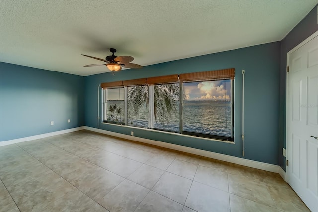 tiled spare room with ceiling fan and a textured ceiling