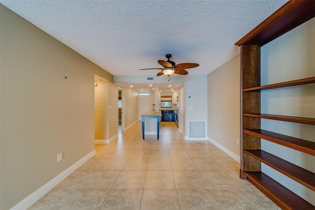 interior space featuring ceiling fan, light tile patterned floors, and a textured ceiling