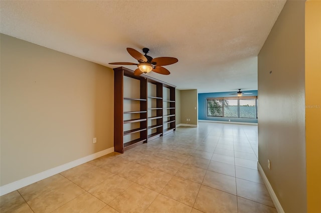 tiled empty room with ceiling fan and a textured ceiling