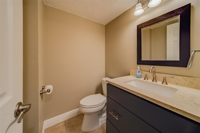 bathroom with tile patterned floors, toilet, a textured ceiling, and vanity