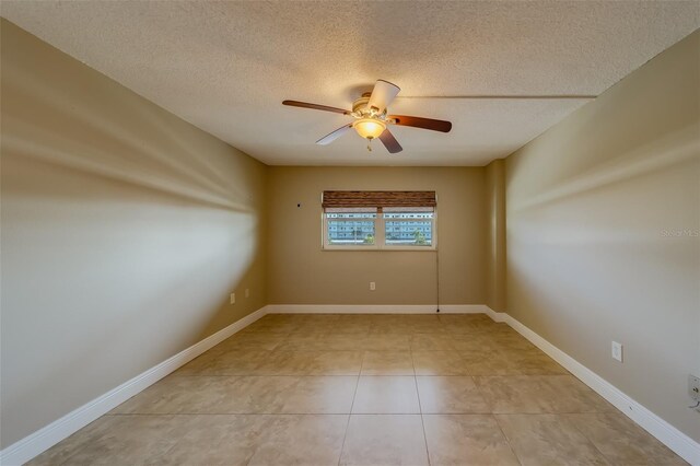 empty room featuring ceiling fan, a textured ceiling, and light tile patterned floors