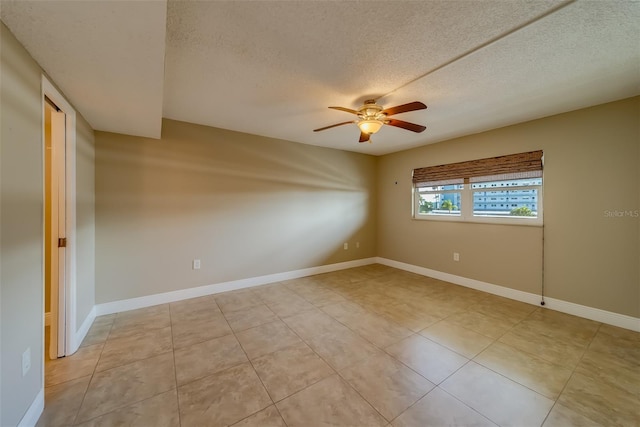 spare room featuring ceiling fan, light tile patterned floors, and a textured ceiling