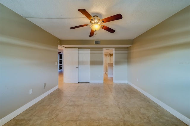 unfurnished bedroom with ceiling fan, a closet, a textured ceiling, and light tile patterned floors