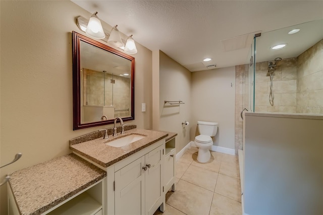 bathroom with vanity, tiled shower, tile patterned floors, and toilet