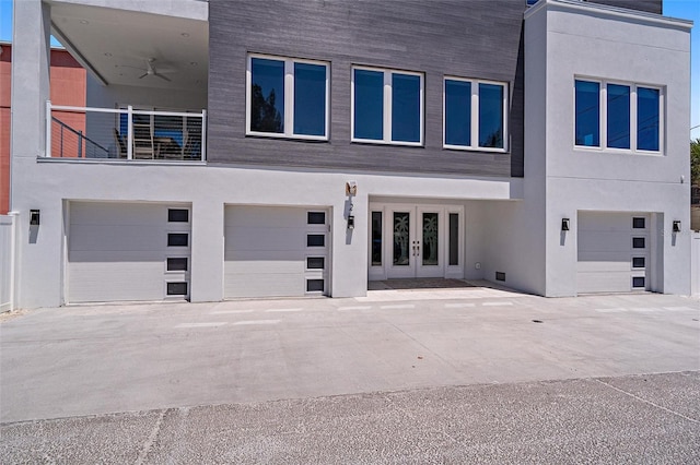 exterior space featuring a garage, driveway, french doors, and stucco siding