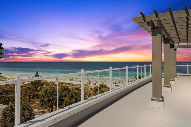 balcony at dusk with a view of the beach and a water view