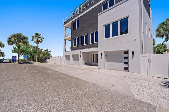 view of building exterior featuring a garage, fence, and driveway