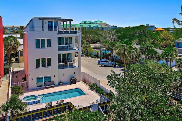 view of pool with a patio, fence, and a pool with connected hot tub