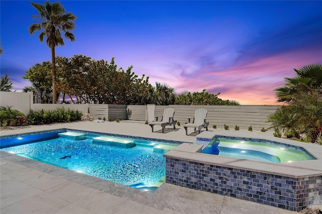 pool at dusk featuring an in ground hot tub, pool water feature, and a patio area