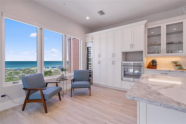 kitchen featuring light stone countertops, a water view, white cabinets, and a view of the beach