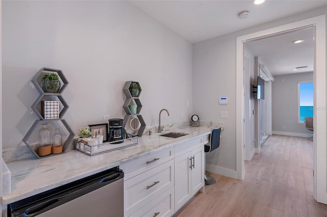 bar featuring white cabinetry, sink, stainless steel dishwasher, light stone countertops, and light wood-type flooring