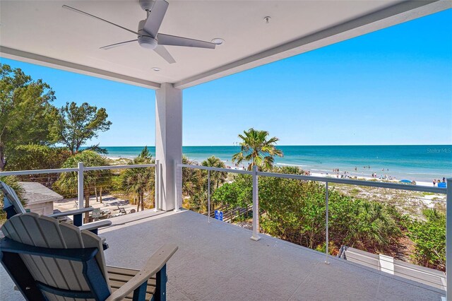 balcony with a water view, ceiling fan, and a beach view