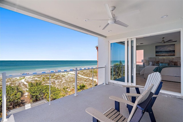 balcony featuring a view of the beach, a water view, and ceiling fan