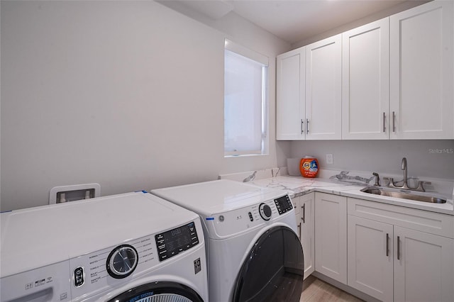 washroom with sink, washer and clothes dryer, light hardwood / wood-style floors, and cabinets