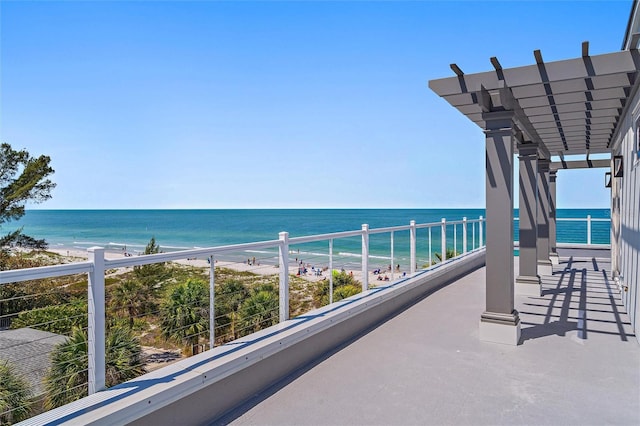 balcony with a water view and a view of the beach