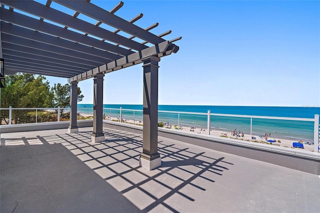 view of patio / terrace featuring a water view, a beach view, and a pergola