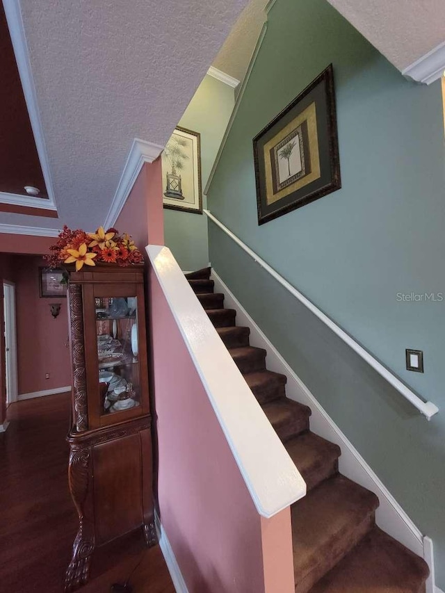 stairs with baseboards, ornamental molding, a textured ceiling, and wood finished floors