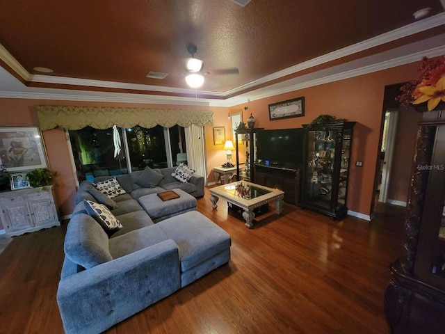 living room with a tray ceiling, crown molding, hardwood / wood-style flooring, and ceiling fan