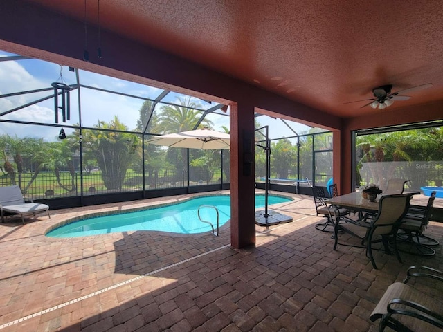 view of swimming pool with a fenced in pool, a patio, glass enclosure, ceiling fan, and fence