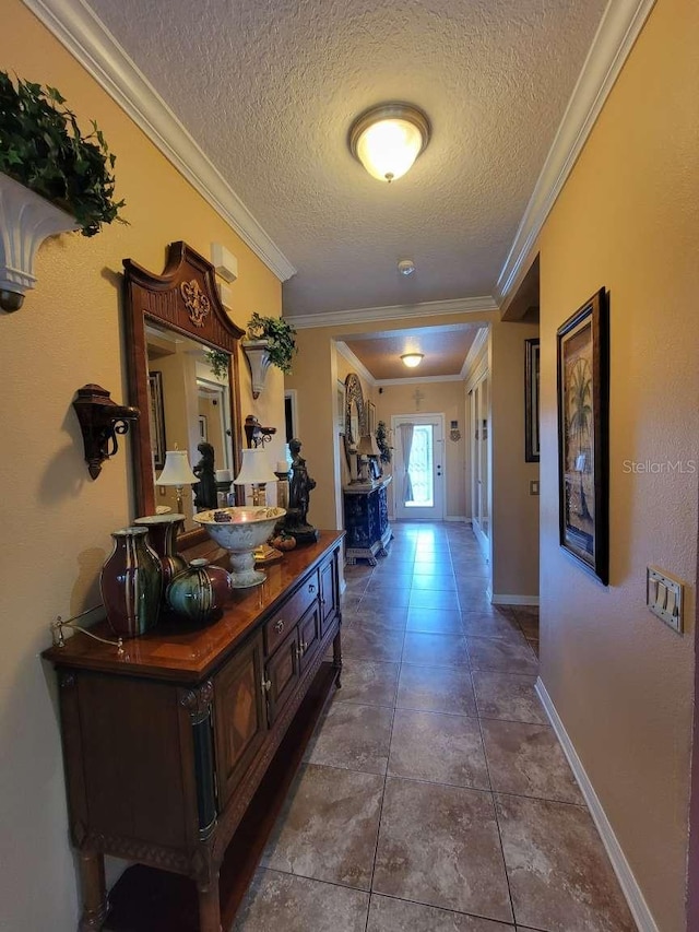 hallway with tile patterned flooring, baseboards, a textured ceiling, and ornamental molding